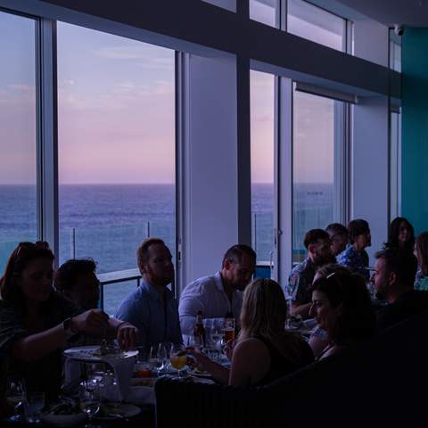 A group of people dining with views over Bondi Beach at Icebergs Dining - one of the best seafood restaurants in Sydney.