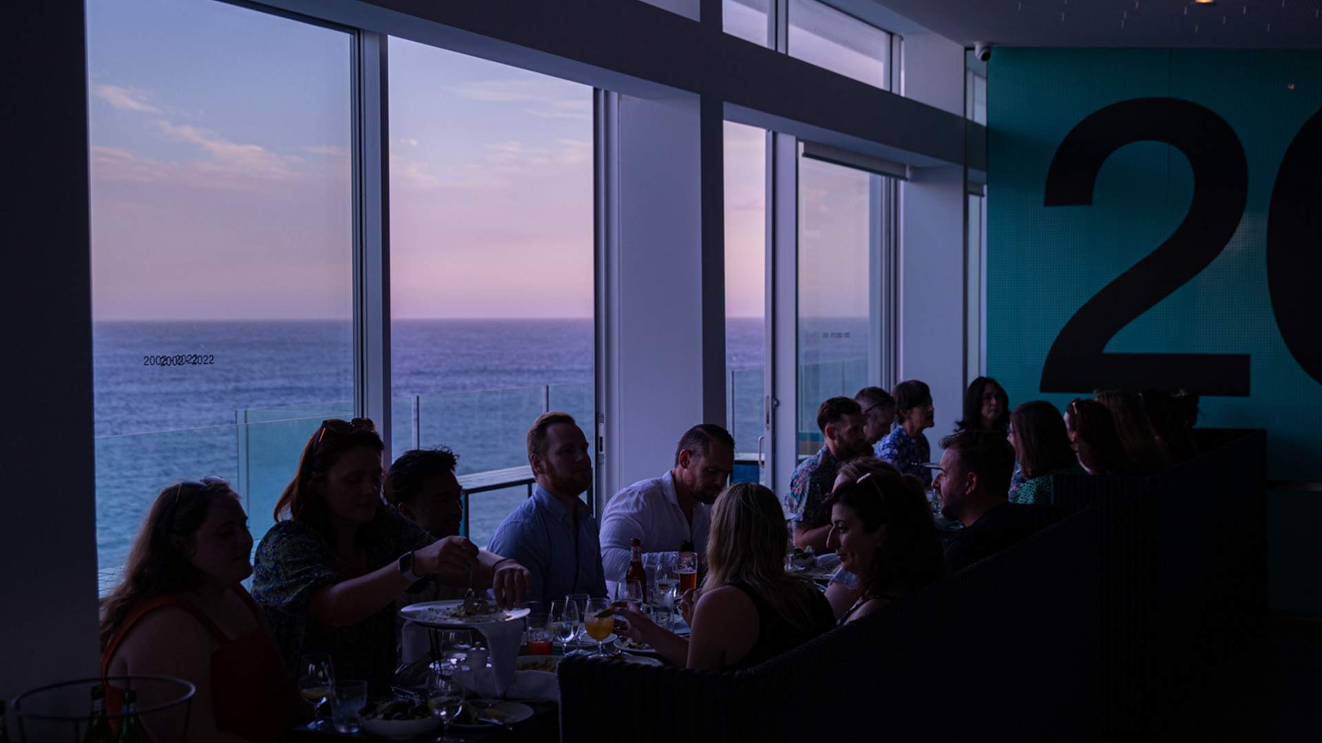 A group of people dining with views over Bondi Beach at Icebergs Dining - one of the best seafood restaurants in Sydney.
