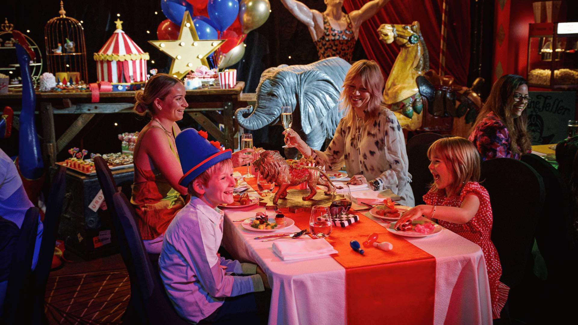 Two children and two women smiling at the Circus Extravaganza High Tea Buffet.
