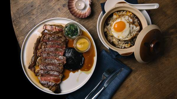 a wooden tabe with a large steak and pot of rice and a fried egg at S'more. home to one of the best steaks in Sydney