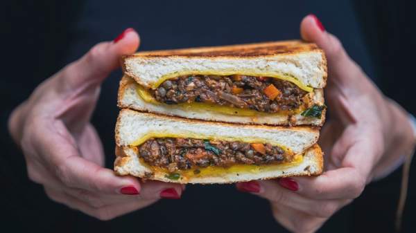 A mushroom, lentil ragu and cheese toastie boasting a rich, herb-forward sauce and melted cheese sandwiched between two slices of classic white toast.