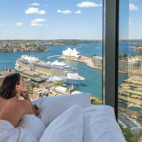 A woman in bed overlooking Sydney Harbour at the Shangri-La Sydney hotel.