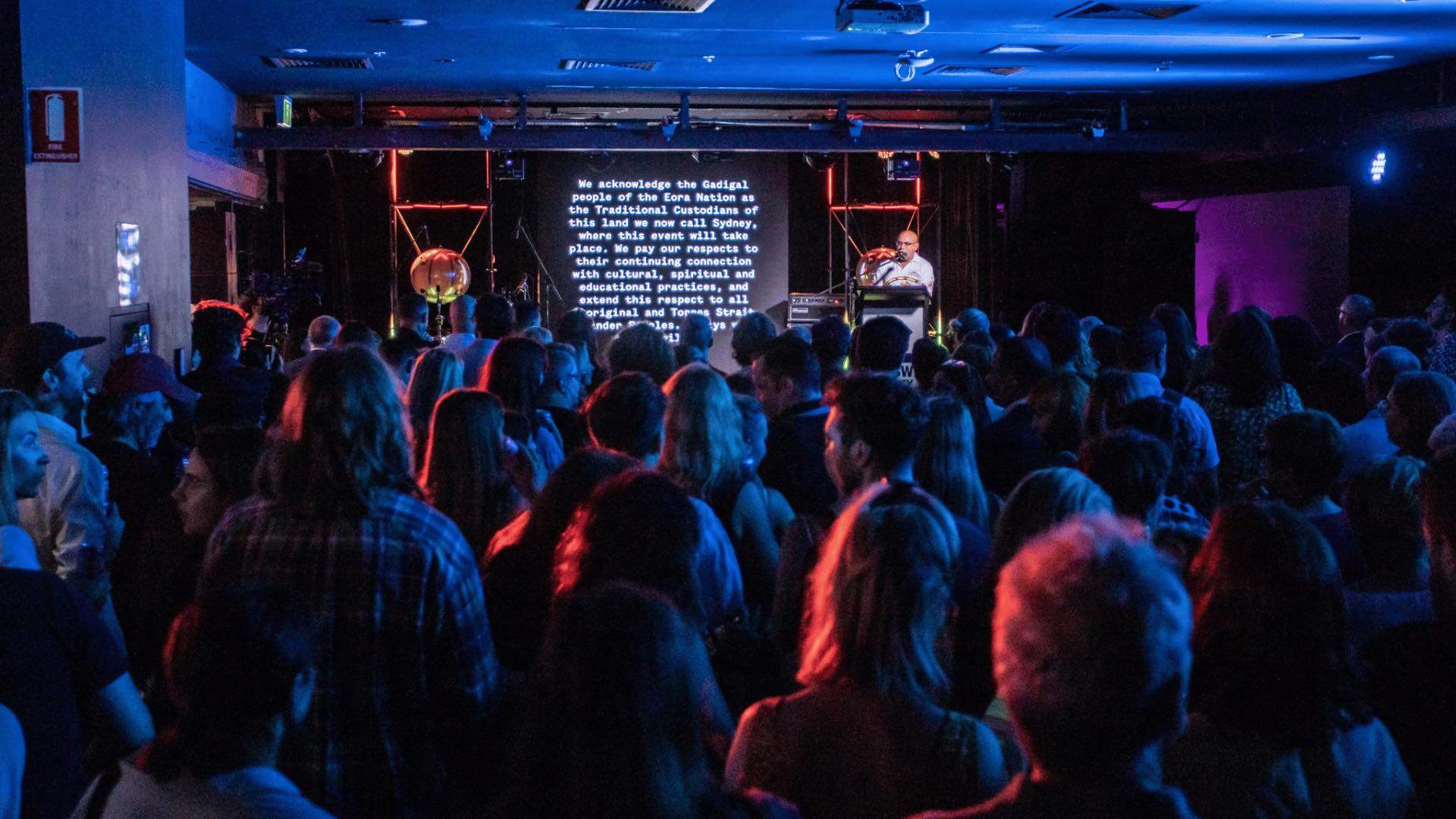 A man presenting a screen with text in front of a crowd.