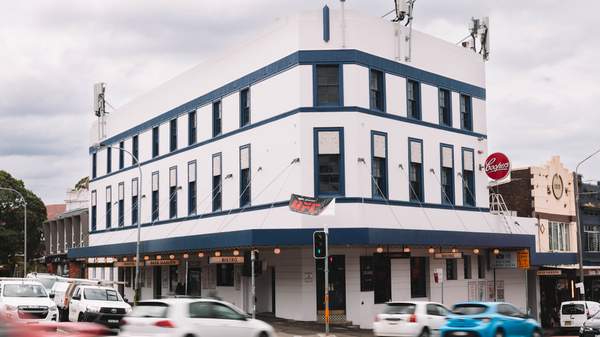 The bright white Empire Hotel sits on Parramatta Road, Annadale as cars drive past