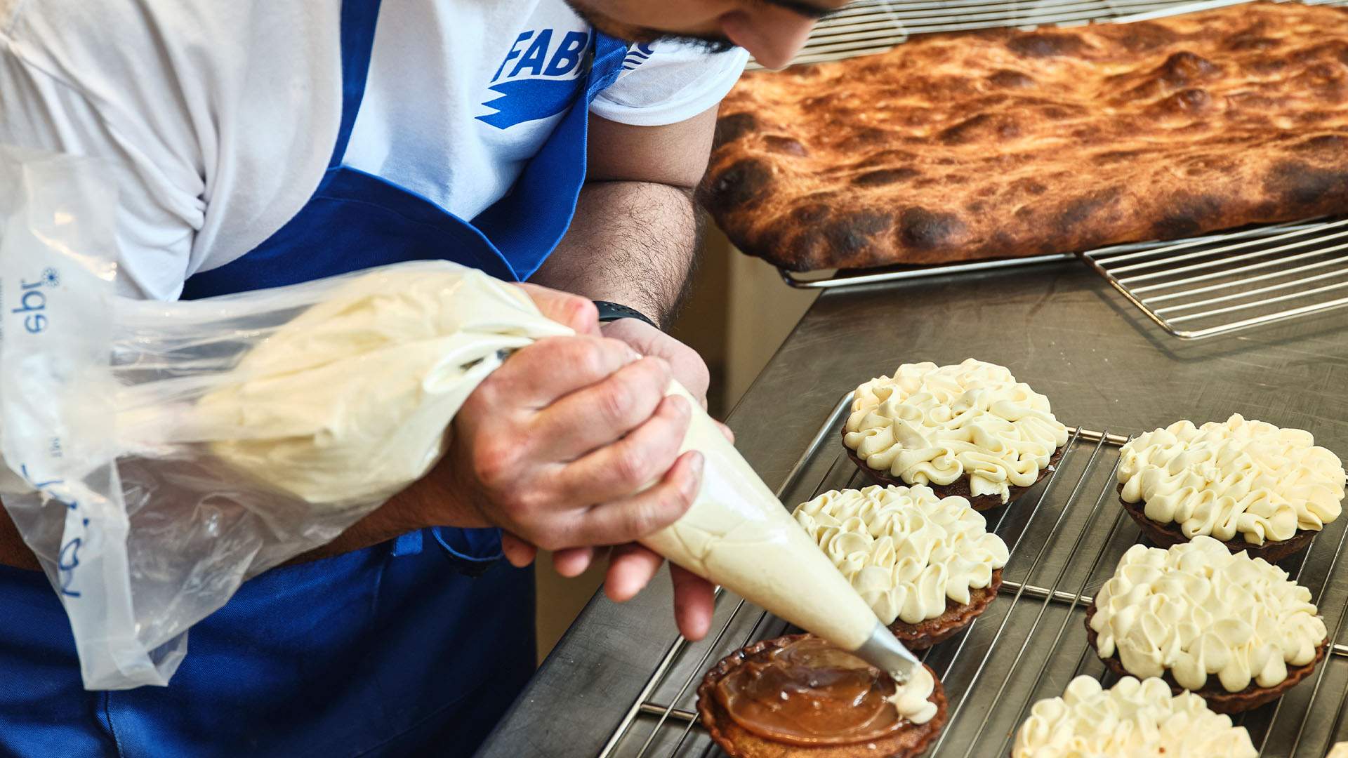 A baker piping banoffee cream onto a tart at Fabbrica Bread Shop, Rozelle