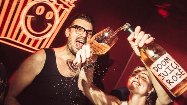 A bottle of Doom Jucie rosé is poured at The Little Guy's red neon-lit karaoke room Poppie's Karaoke