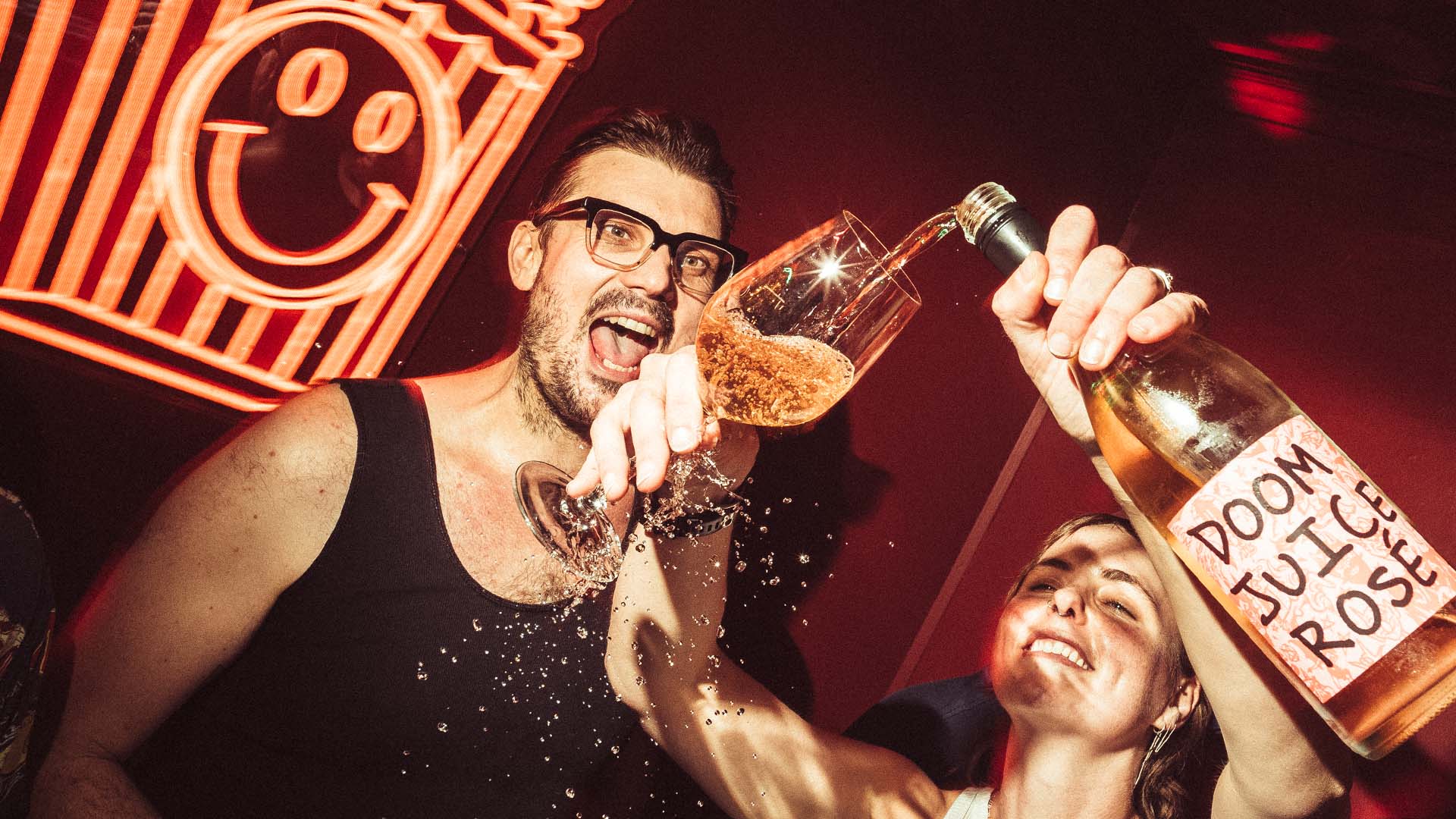 A bottle of Doom Jucie rosé is poured at The Little Guy's red neon-lit karaoke room Poppie's Karaoke