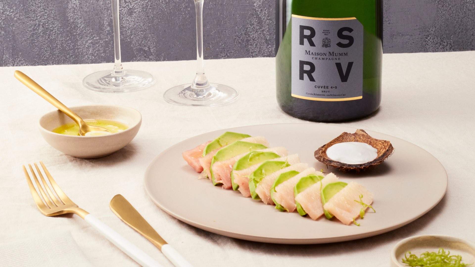 A bottle of Maison Mumm's RSRV wine and an entree on a table.