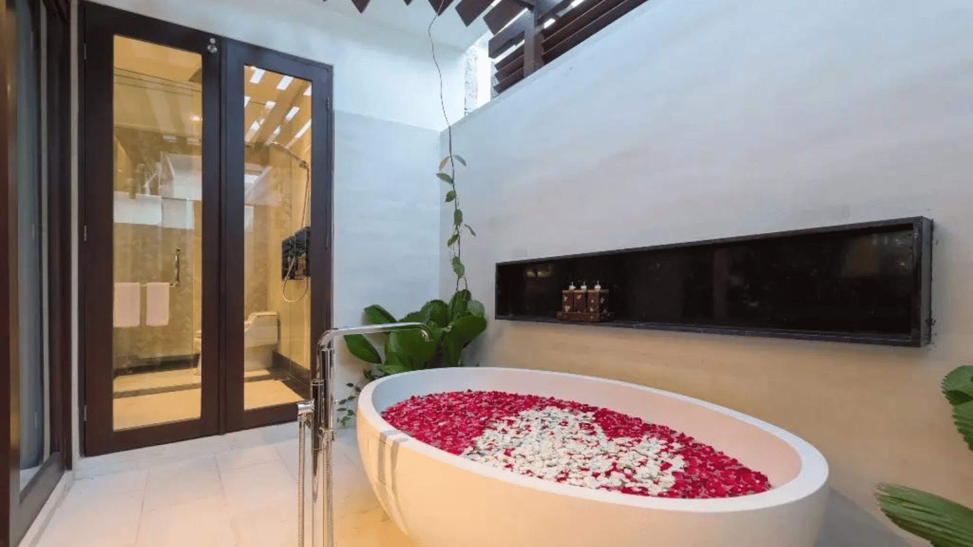 A photo of a bathtub in a villa at Prasana filled with rose petals.