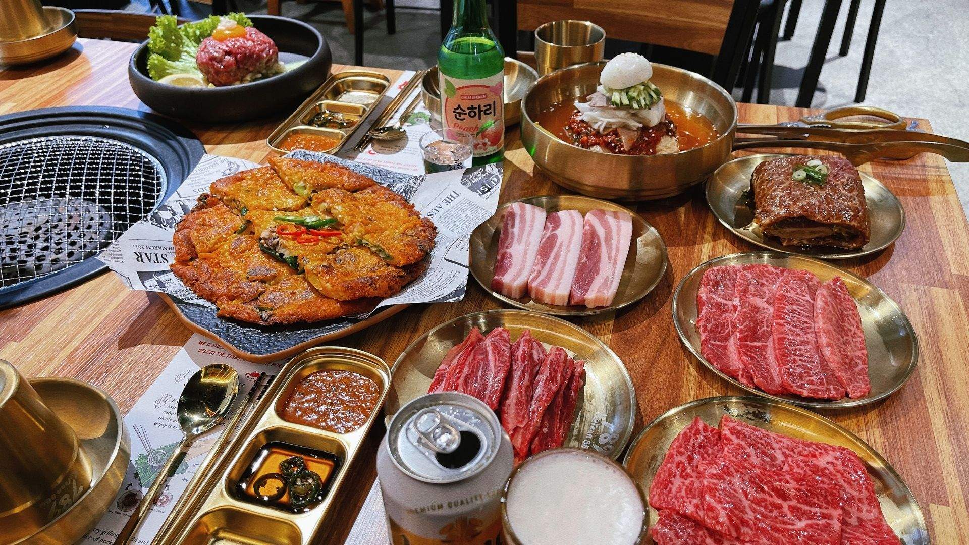 A food spread — including premium cuts of meat, a seafood pancake and soju — from the menu of Darling Square's 789 Korean BBQ. 
