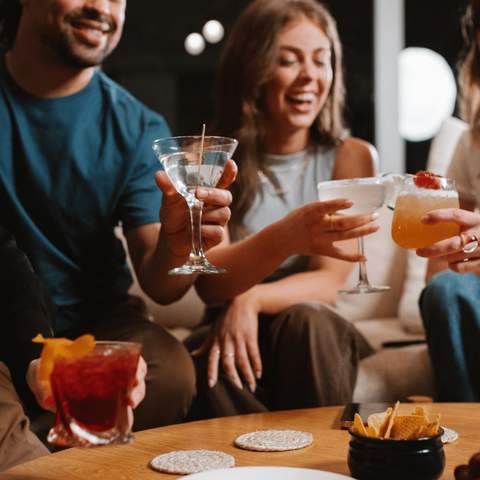 Four people with various cocktails at home.