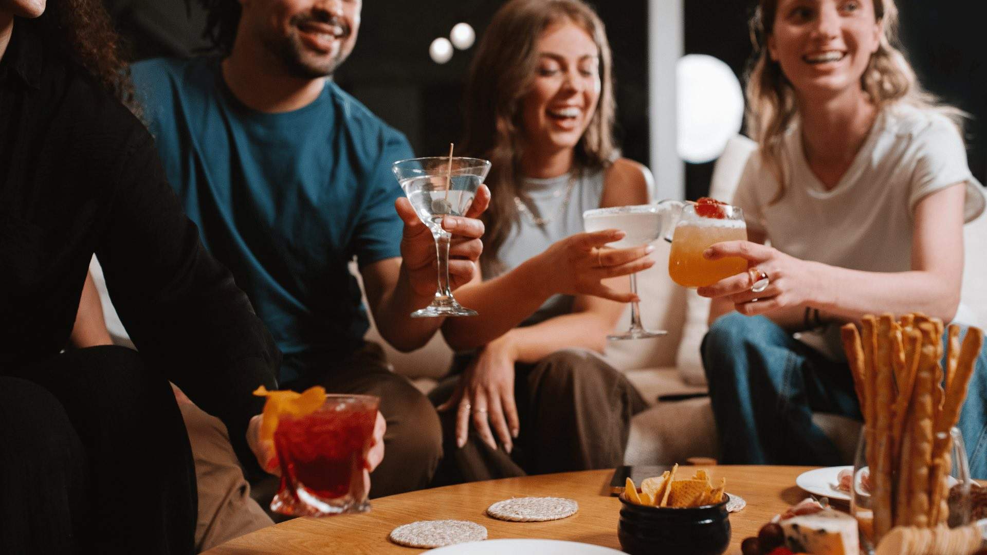 Four people with various cocktails at home.
