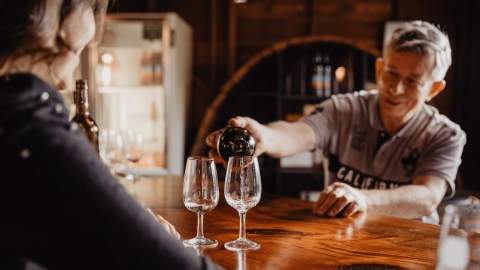 A man pouring two glasses of wine in a winery.