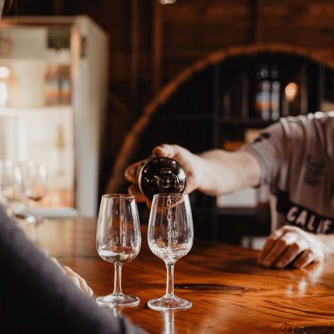 A man pouring two glasses of wine in a winery.