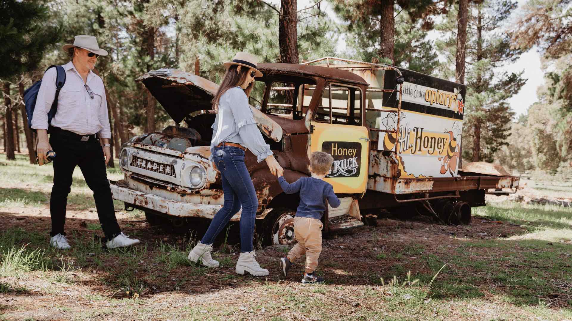 A family with a toddler in front of a honey truck.