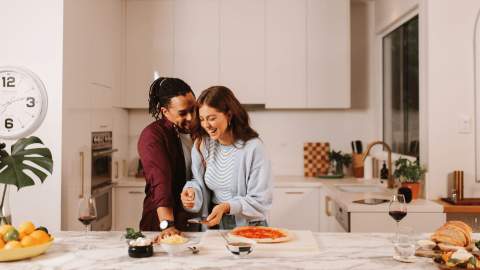 A couple laughing in the kitchen.