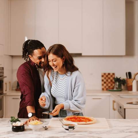 A couple laughing in the kitchen.