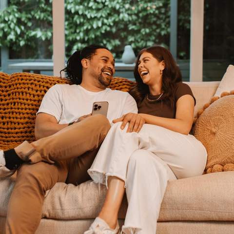 A couple laughing on the couch.