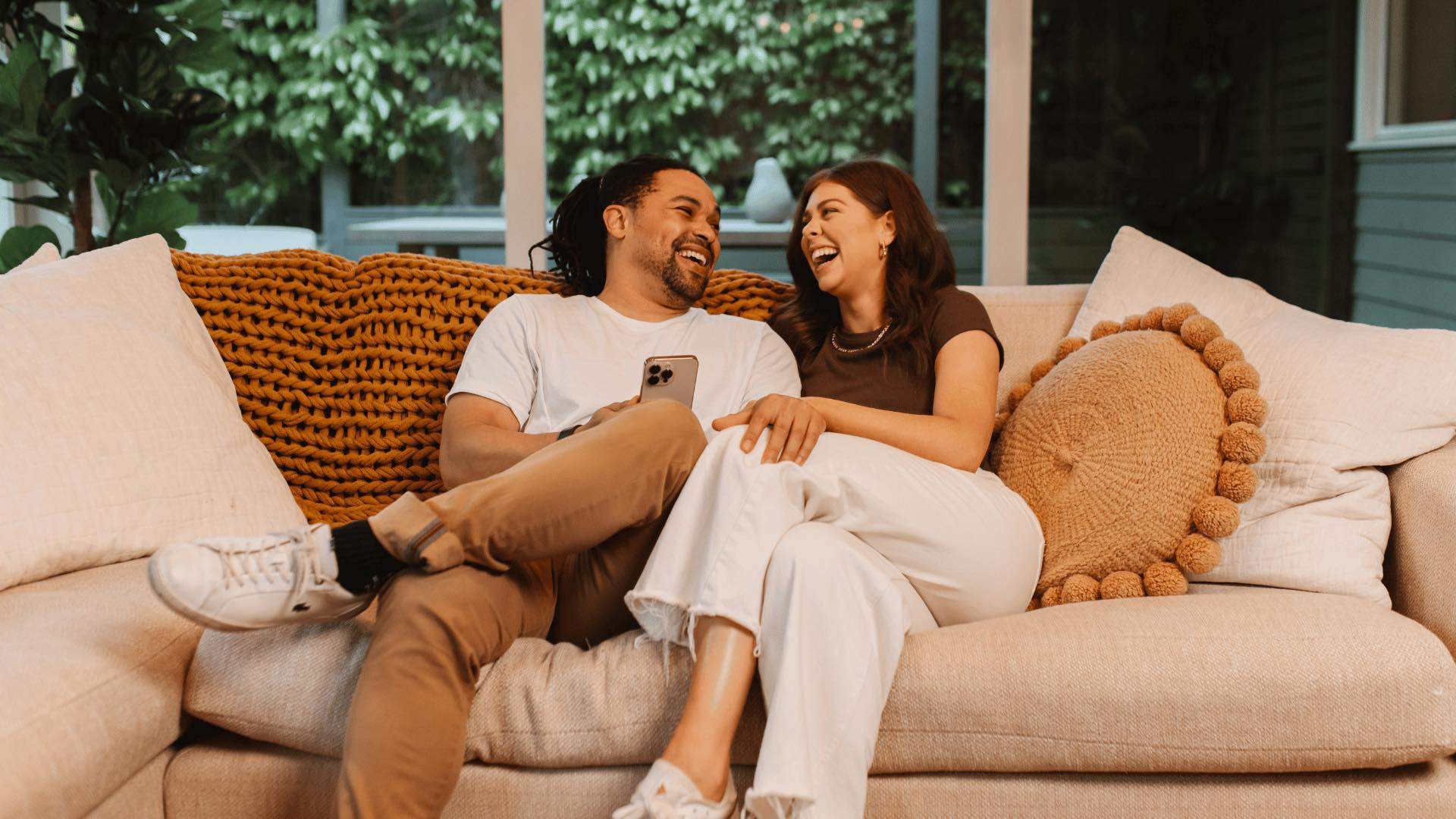 A couple laughing on the couch.