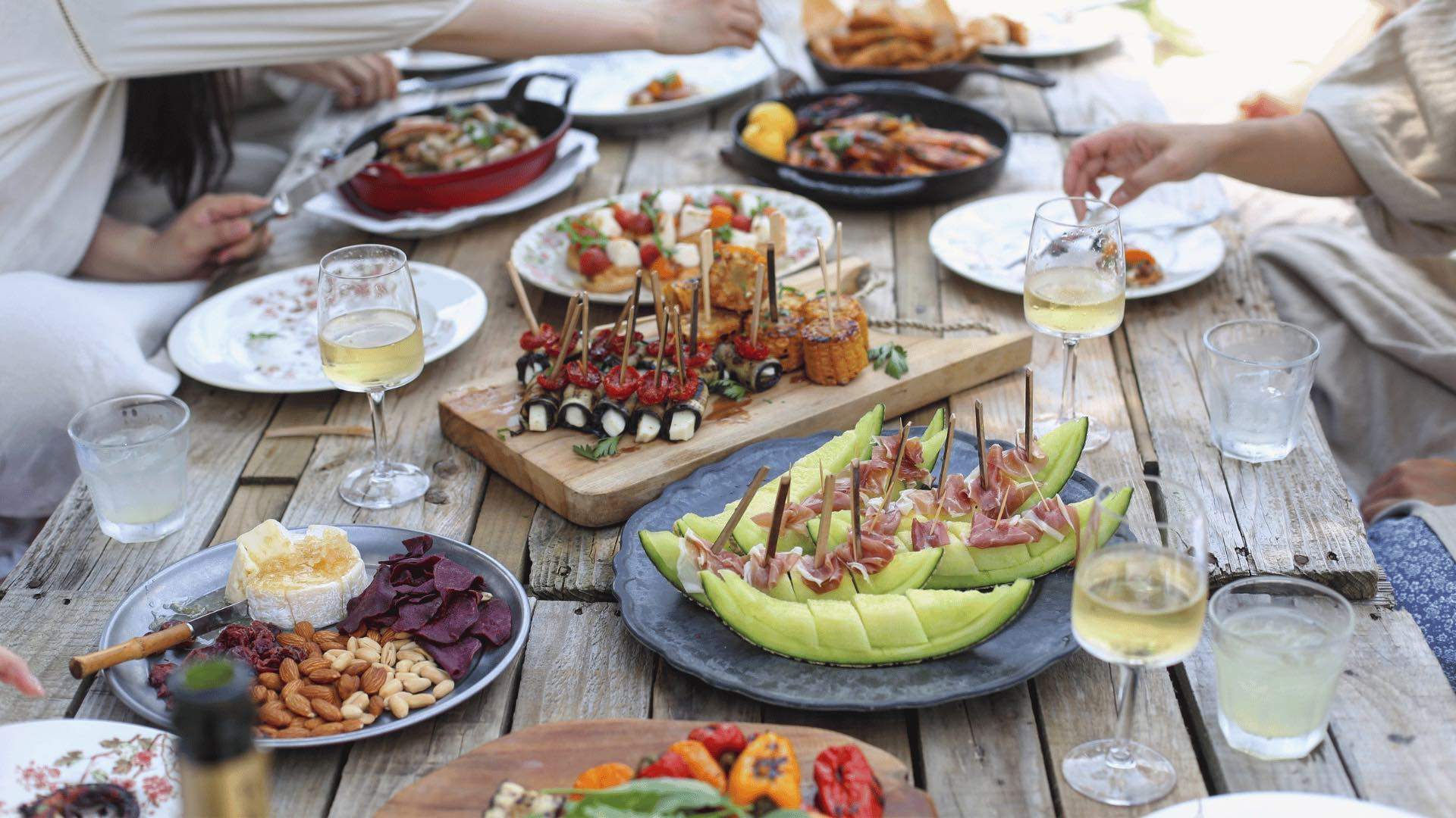 Various appetisers on a dining table with glasses of wine.
