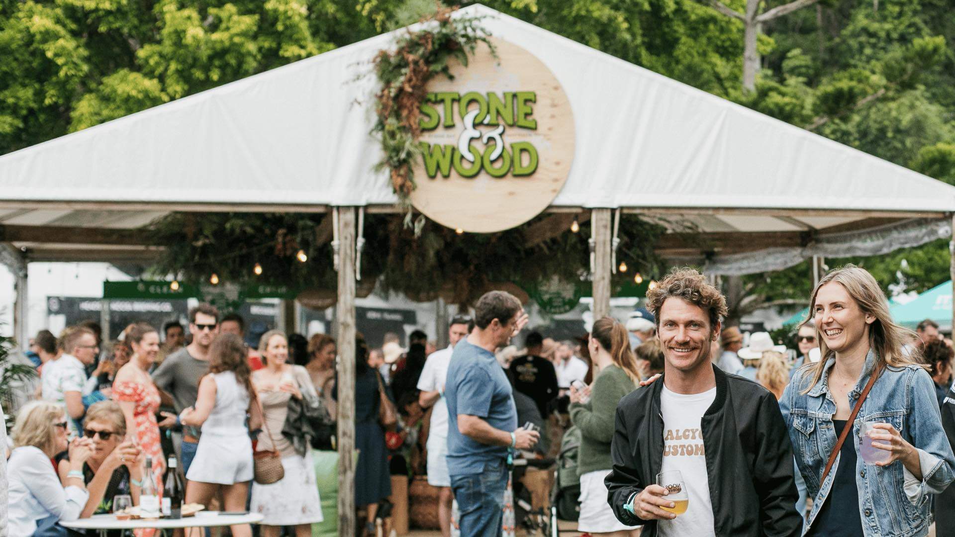 People enjoying drinks in front of a Stone & Wood tent at the Noosa Eat and Drink Festival.