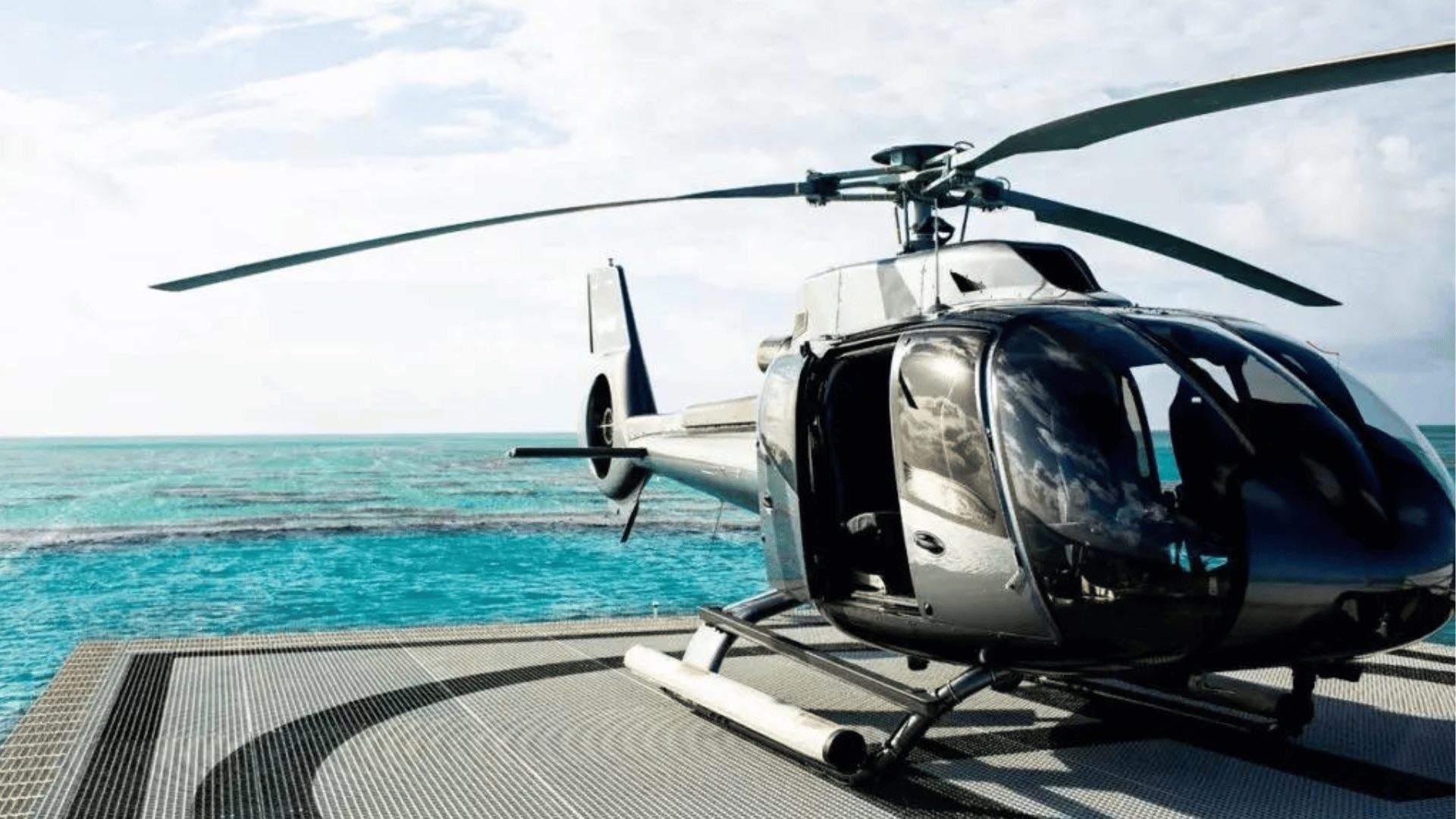 A helicopter on a private pad by the water.