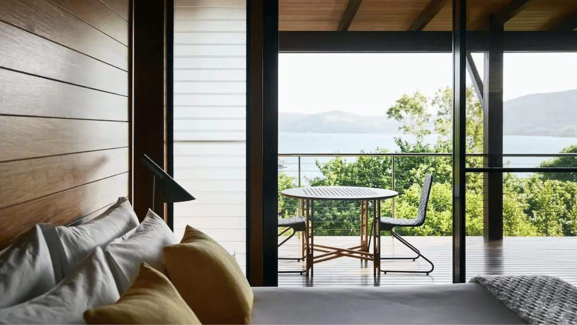 A king bed and terrace overlooking the ocean at qualia resort on Hamilton Island.