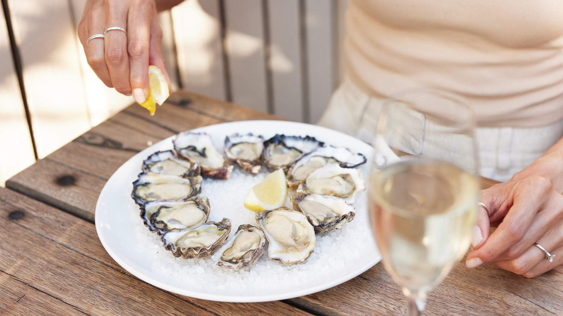 A patron squeezes a lemon onto a plate of a dozen oysters at The Erko.