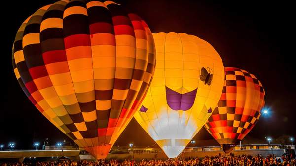Three hot-air balloons above a crowd.