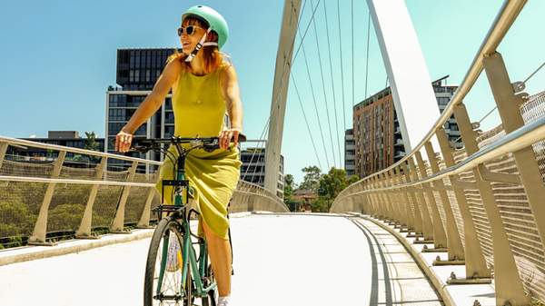 A woman cycling on a bridge.