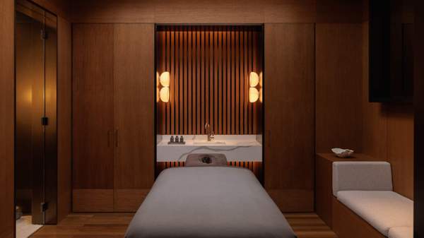 A massage room at The Capella Sydney's Auriga Spa. A massage table is in the middle of the beautiful timber-lined space with soft grey details.