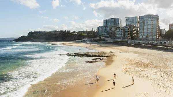 Aerial view of young people playing a ball game along the water at Newcastle Beach