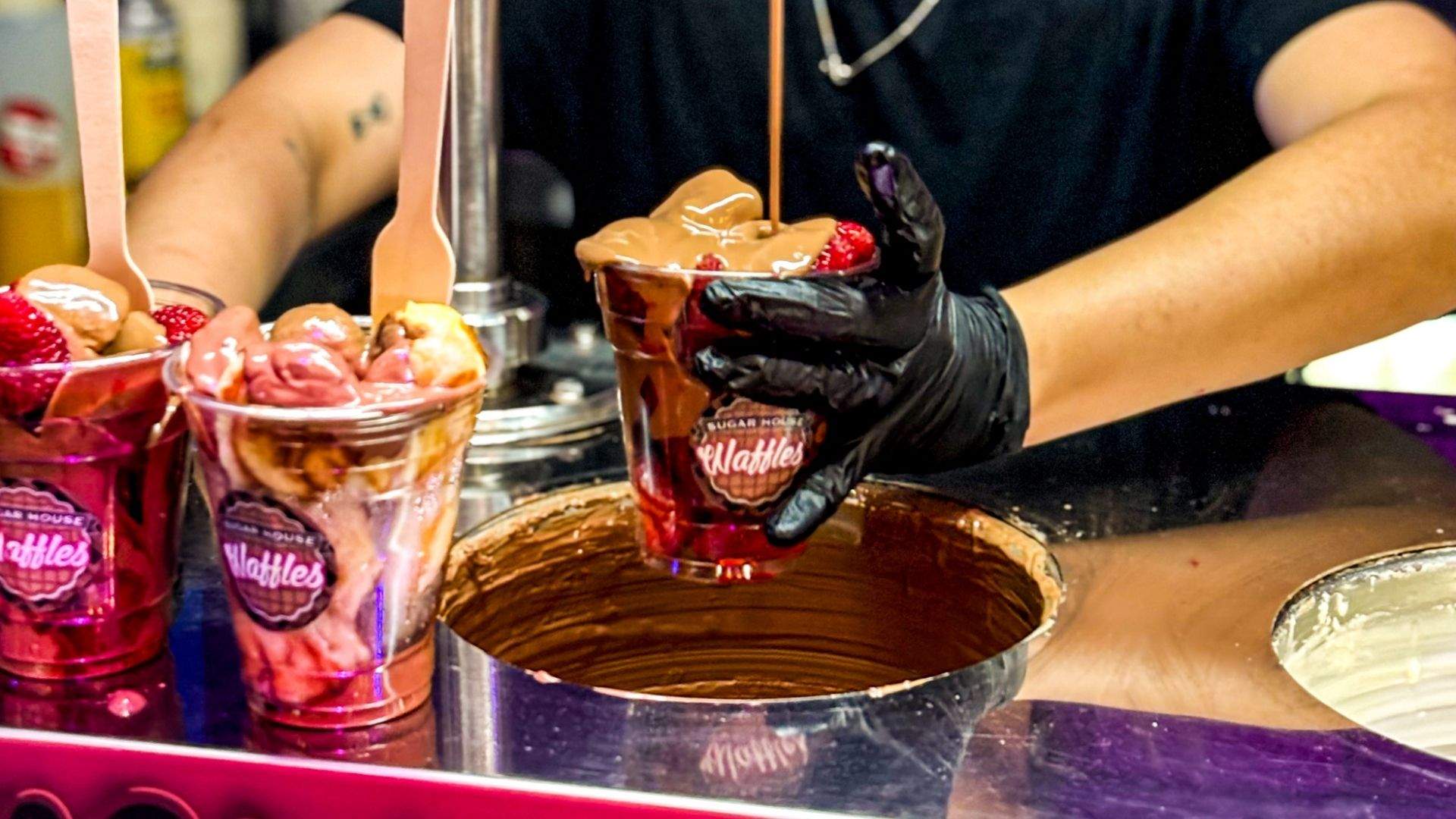Chocolate pouring onto a strawberry fruit cup available at Spicetown night markets in Sefton.