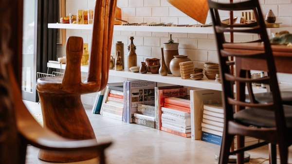 A collection of mid-century modern homewares including vases, ceramic sculptures and design books stacked artfully on shelves.