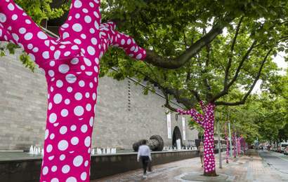 Background image for Yayoi Kusama Is Turning 60-Plus Melbourne Trees Into Her Latest Polka Dot-Covered (and Bright Pink) Artwork