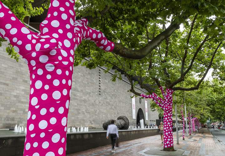 Background image for Yayoi Kusama Is Turning 60-Plus Melbourne Trees Into Her Latest Polka Dot-Covered (and Bright Pink) Artwork