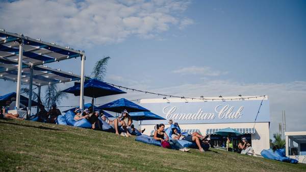 People lounge on blue beanbags on a hill with a Canadian Club tent in the background