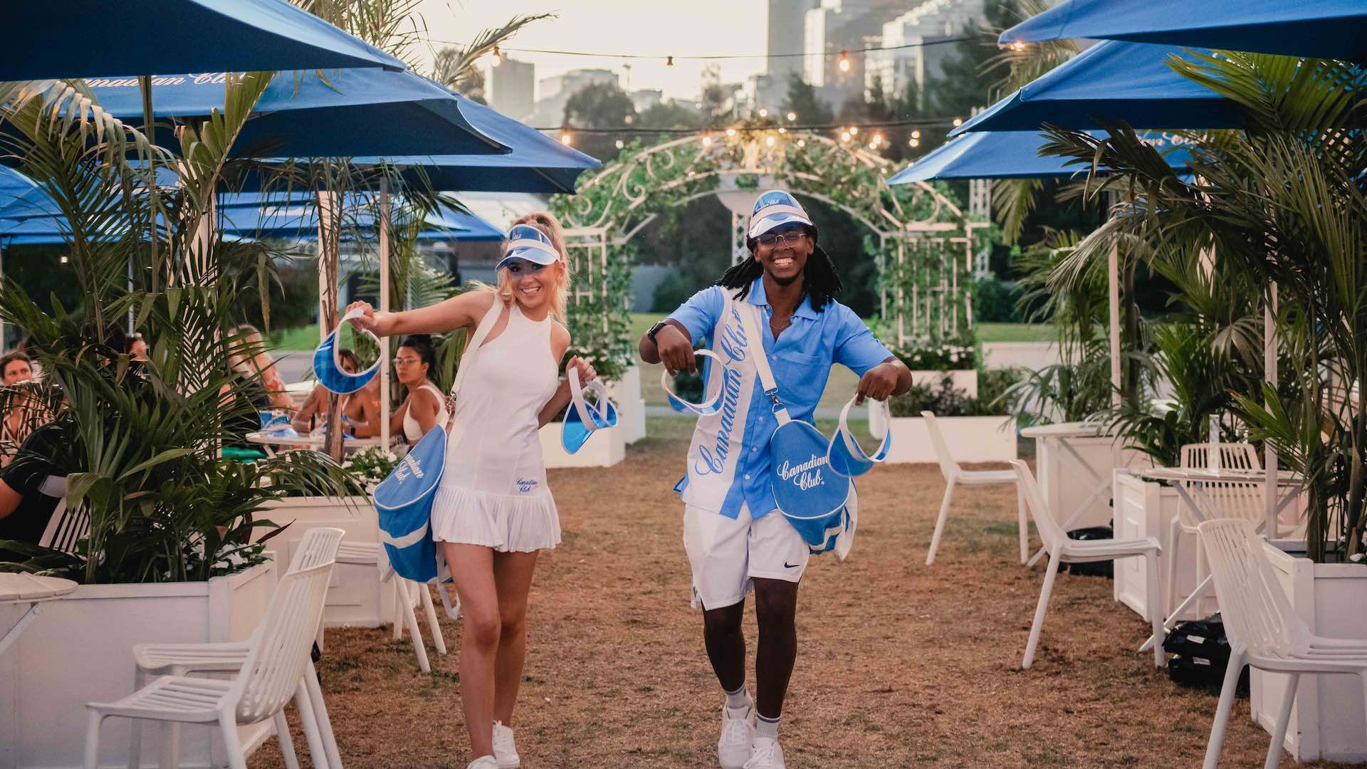 Two people wearing blue visors and looking happy in tennis couture.