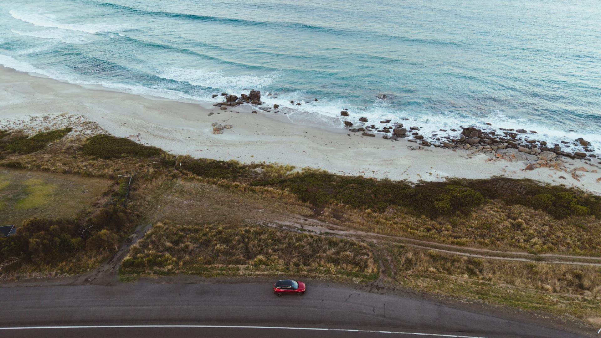 Red SUV parked at a Tasmanian coastal boat ramp overlooking the water