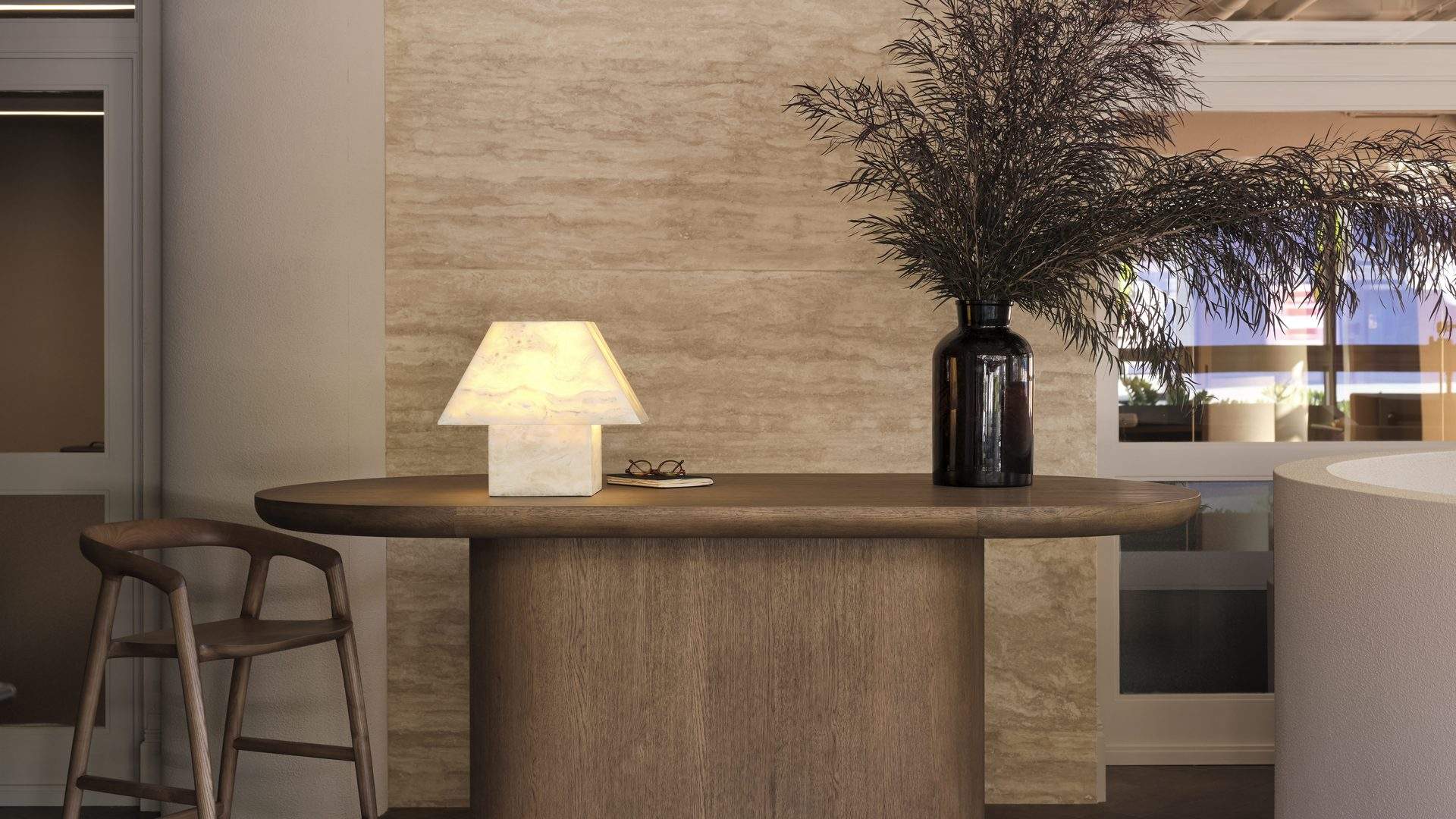 Timber front desk with alabaster lamp and travertine wall at Bodylove Pilates Neutral Bay
