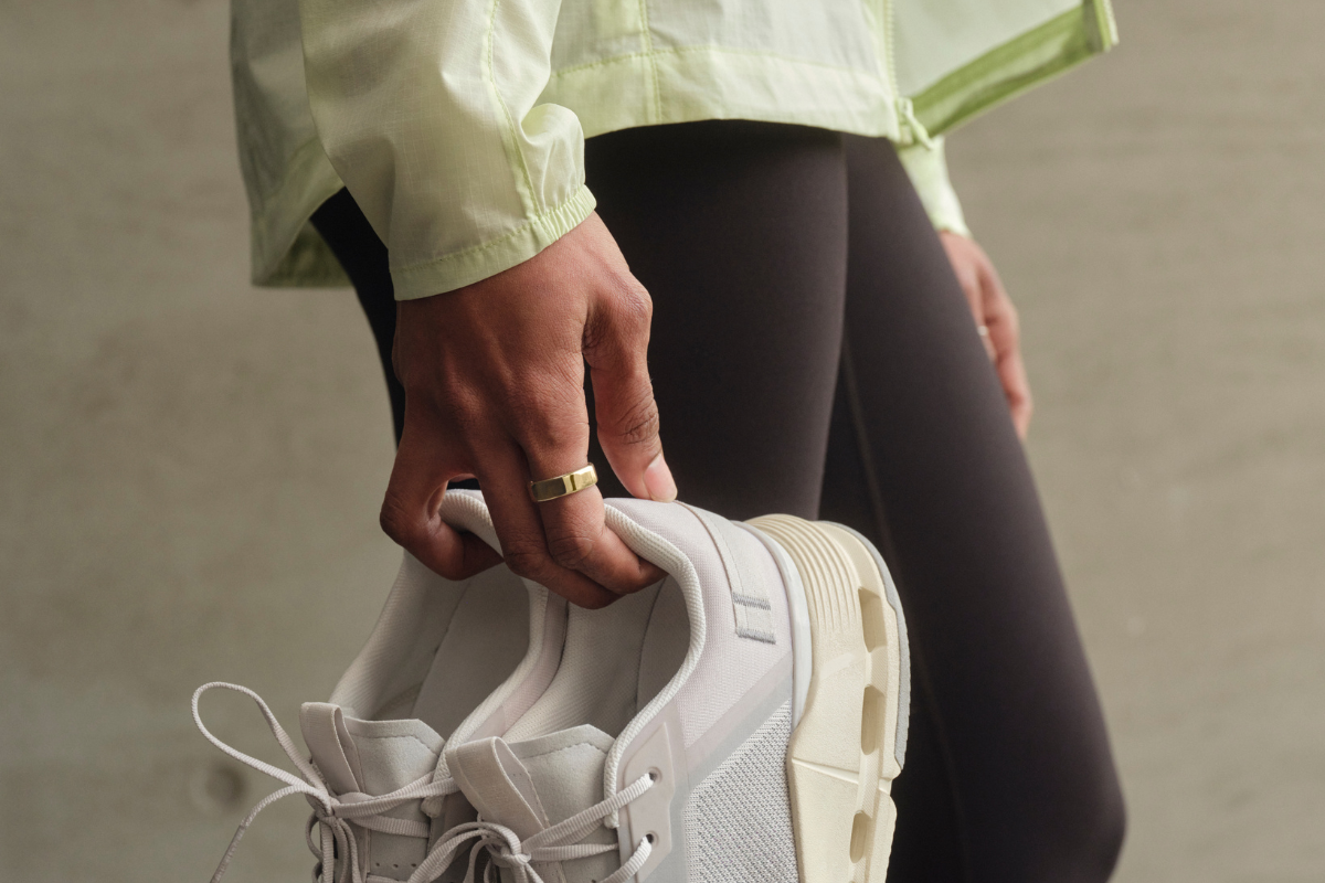 Close-up of person holding a pair of sneakers dressed in activewear.