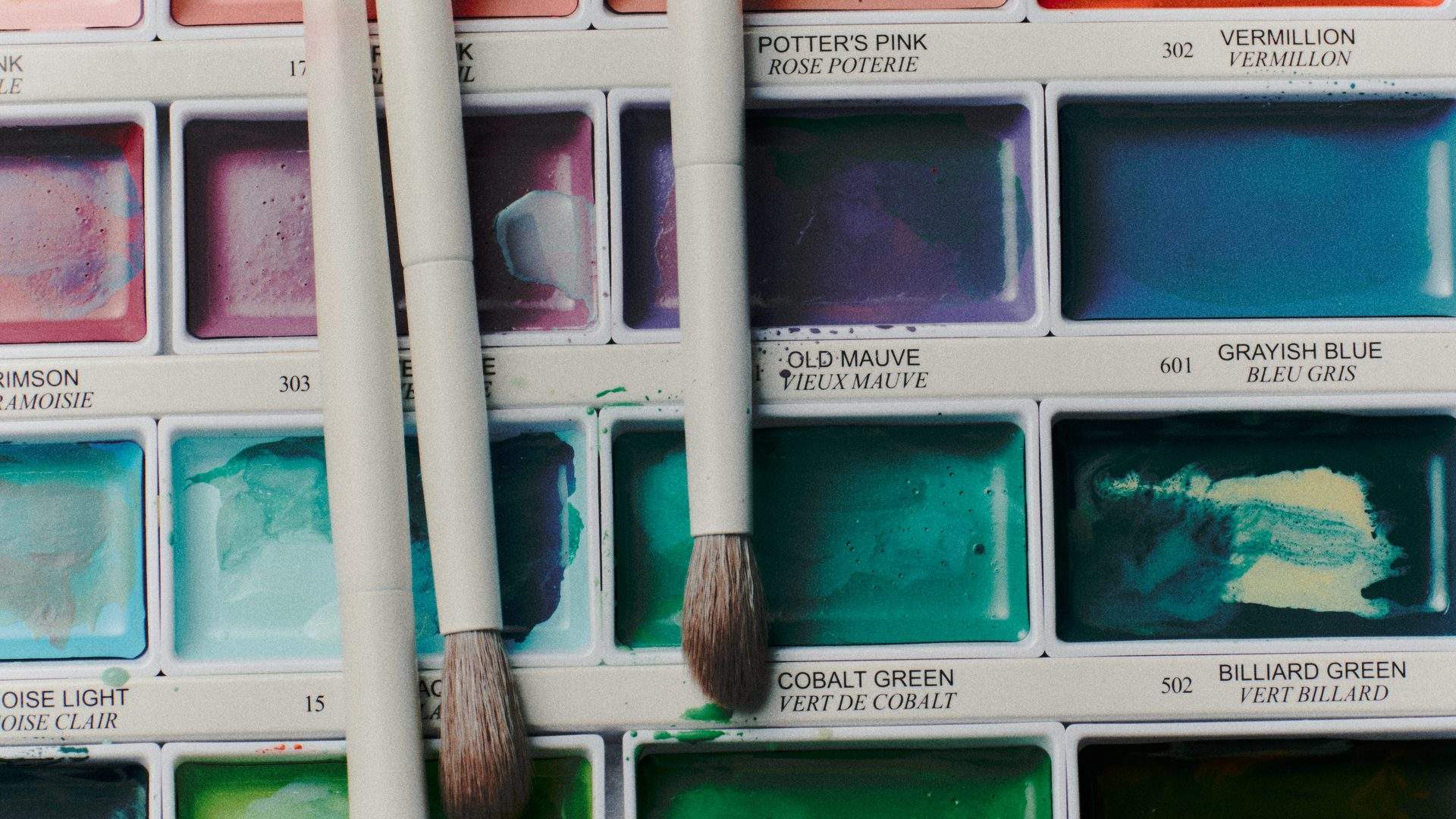 Makeup brushes resting on a watercolour paint palette