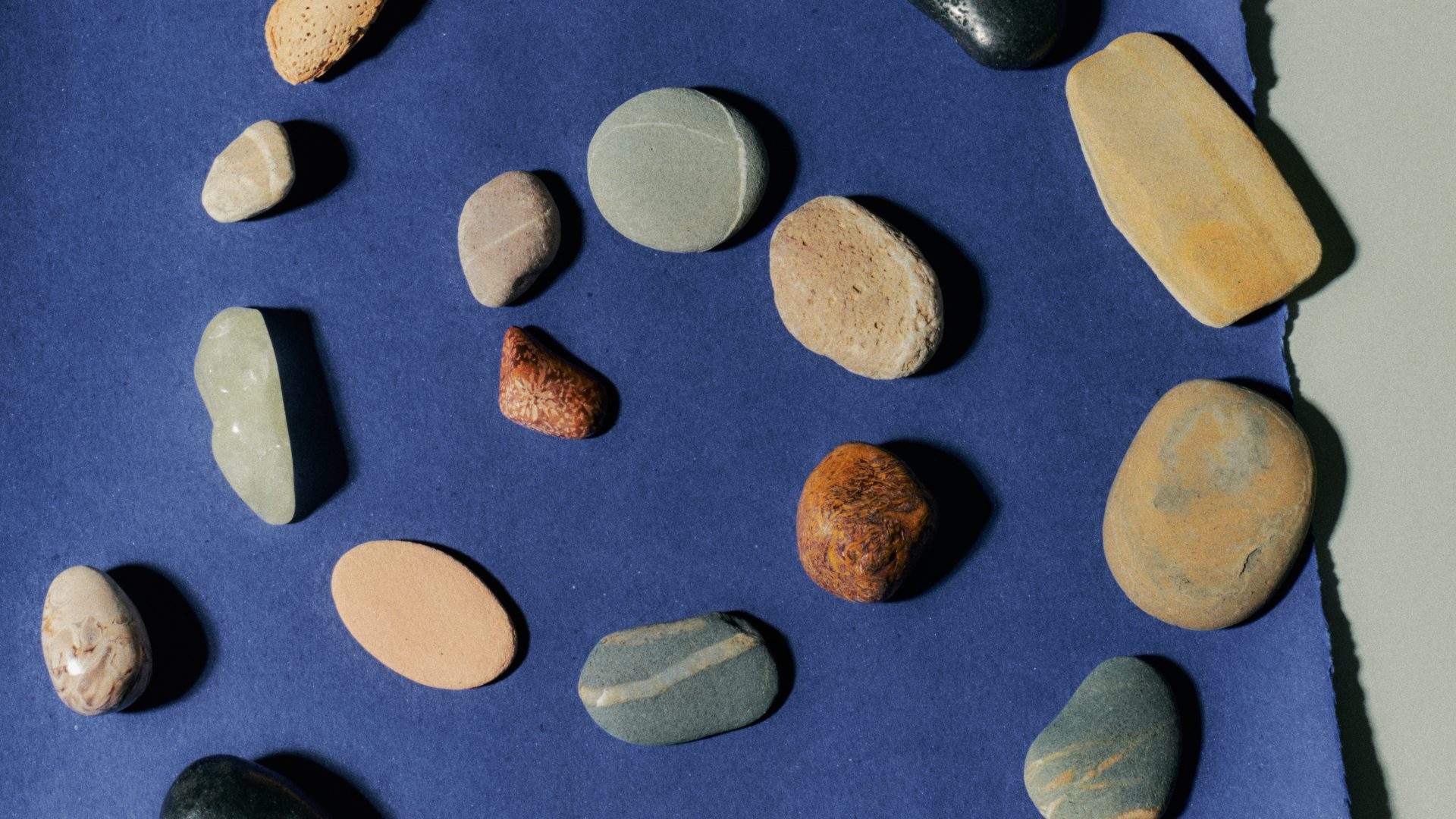 Smooth stones arranged in a spiral on blue paper