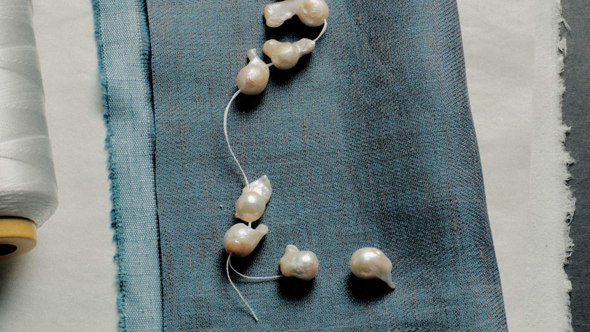 Baroque pearls threaded on string across blue fabric