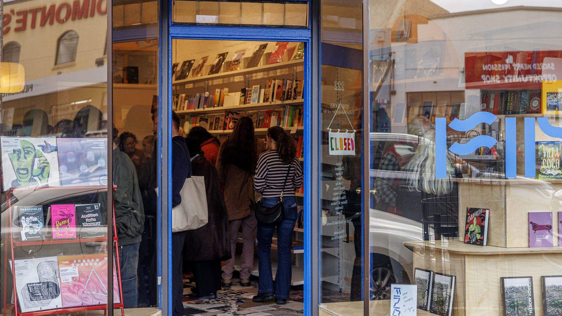 The blue-framed shopfront of Fino Books on St Georges Road, Fitzroy North, with Piedimonte's reflected in the window