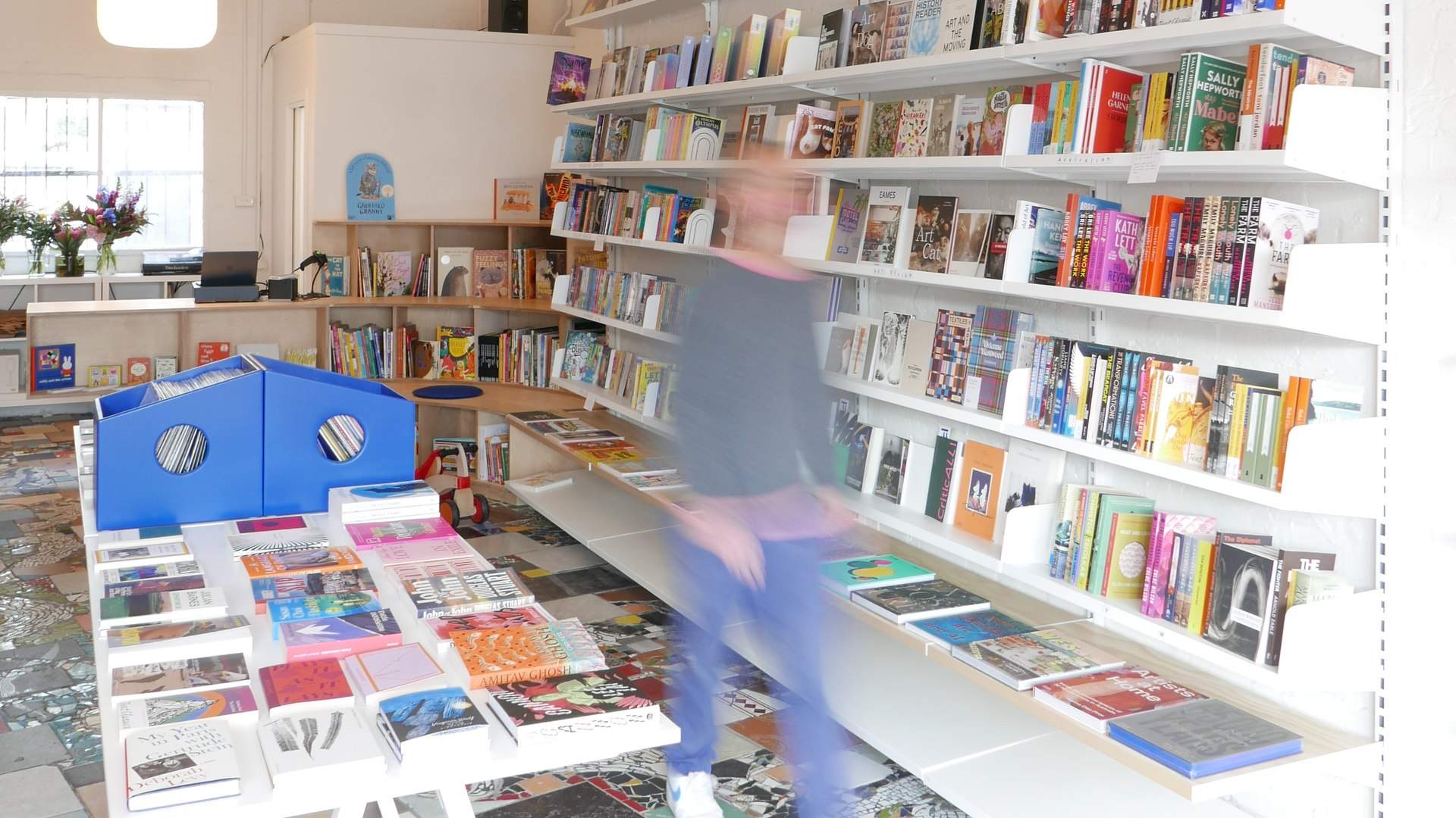 Inside Fino Books, with white shelving, a blue record crate and the original patchwork tiled floor