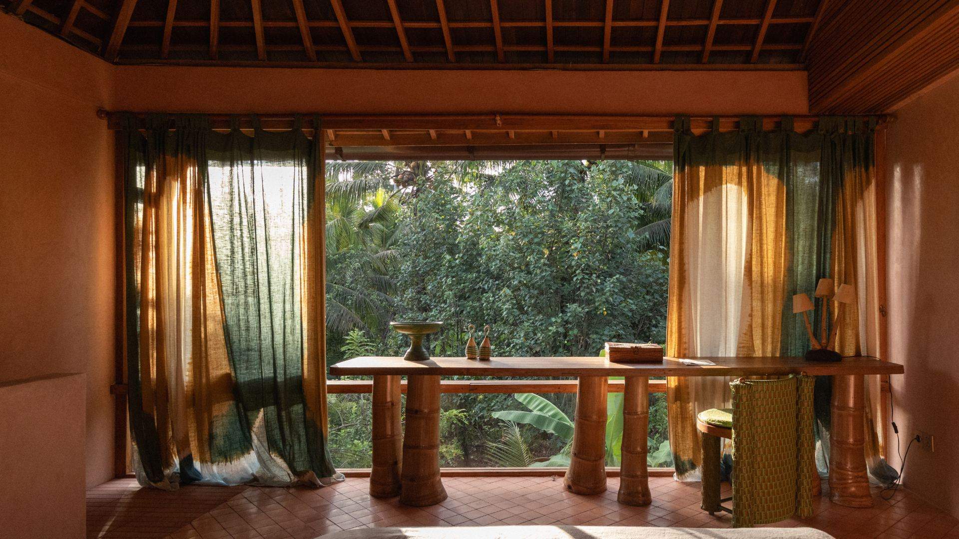 Pink-plastered suite at Moon Gang Ubud with a long timber desk facing a wide window onto the jungle