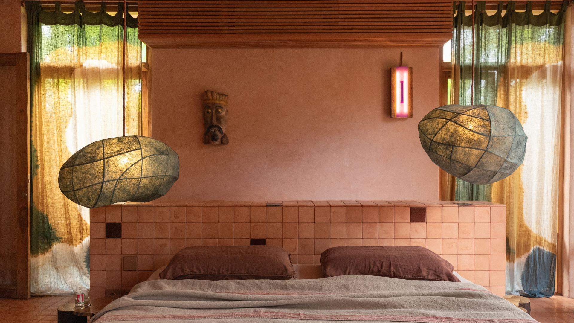 Bed with woven pendant lights and a tiled headboard in the Midnight Runners suite at Moon Gang Ubud