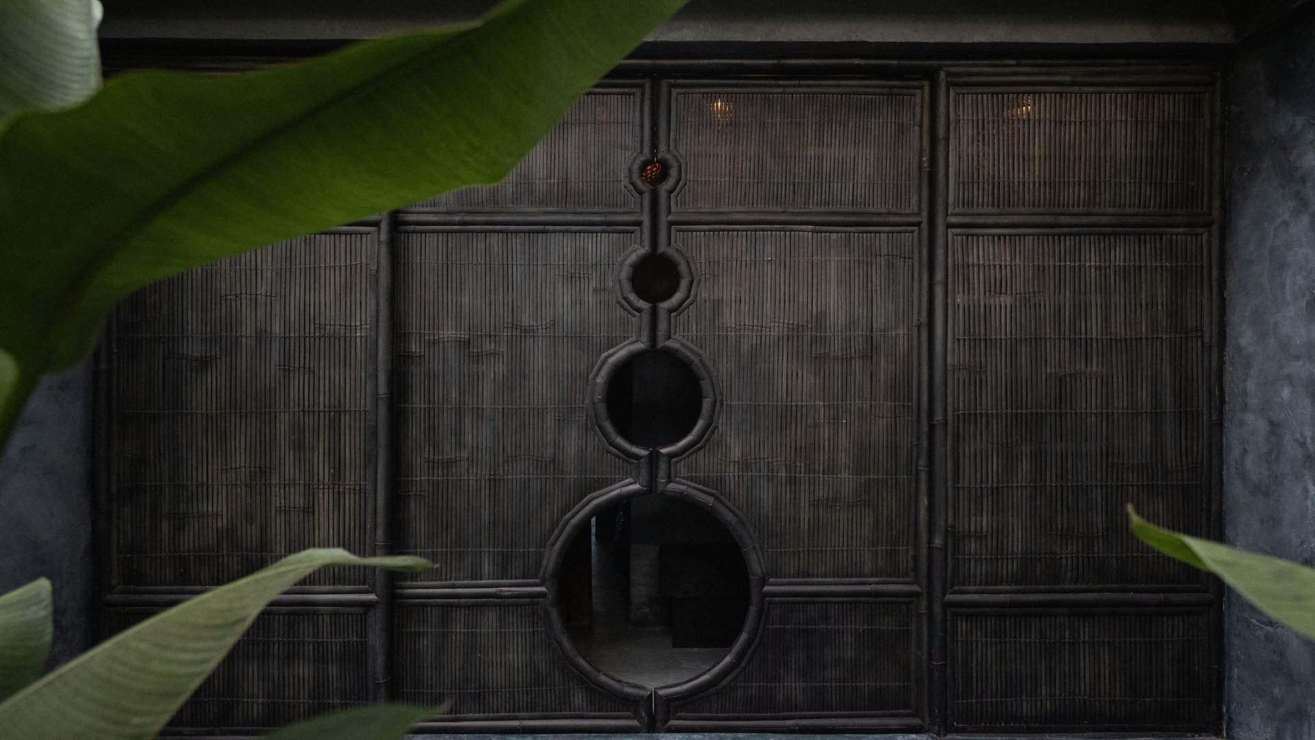 Dark timber doors with circular cut-outs at the Wellness Lab spa at Moon Gang Ubud